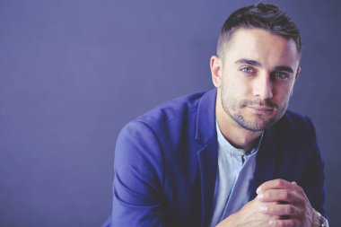 Gri arka planda yalnız oturan genç iş adamı.