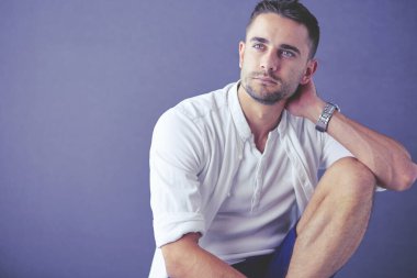 Gri arka planda yalnız oturan genç iş adamı.