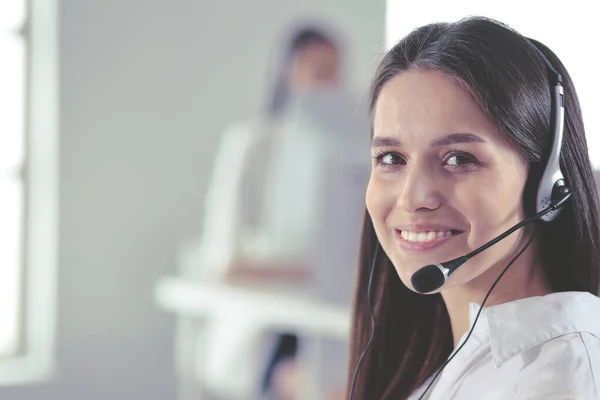 Mujer de negocios sonriente u operador de línea de ayuda con auriculares y computadora en la oficina — Foto de Stock