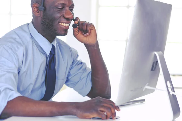 Afrikaans Amerikaans zakenman op headset werken op zijn laptop — Stockfoto