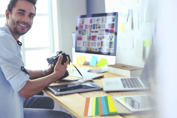 Porträt eines jungen Designers, der im Grafikstudio vor Laptop und Computer sitzt, während er online arbeitet. — Stockfoto