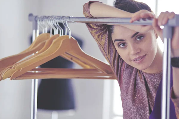 Mooie jonge stylist bij rek met hangers — Stockfoto