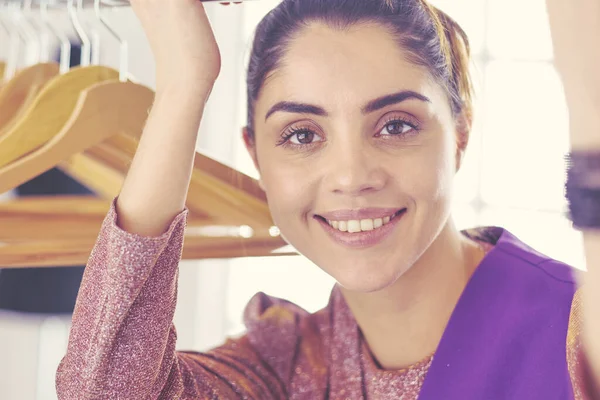 Mooie jonge stylist bij rek met hangers — Stockfoto