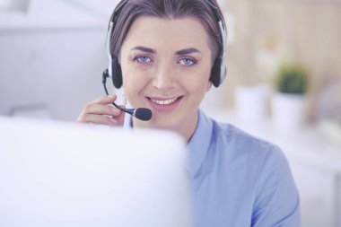 Ofisinde kulaklık takmış, telefon operatörü olarak çalışan ciddi ve güzel bir genç kadın.