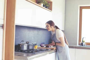 Mutfakta yemek yapmak için tablet bilgisayar kullanan genç bir kadın.