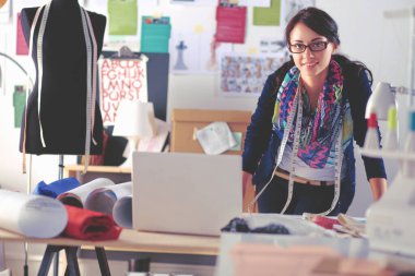 Güzel genç moda tasarımcısı stüdyoda duruyor.