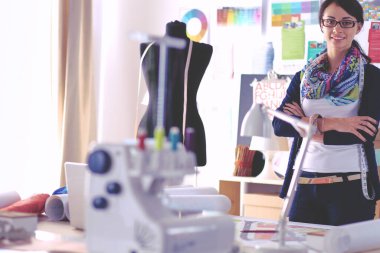 Güzel moda tasarımcısı stüdyoda duruyor.