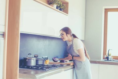 Mutfakta yemek yapmak için tablet bilgisayar kullanan genç bir kadın.