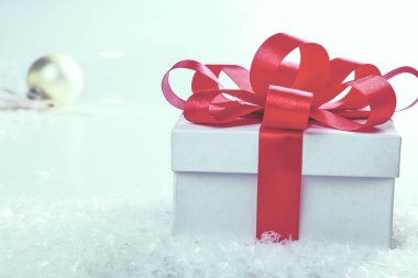 Kırmızı kurdeleli beyaz hediye kutusu.