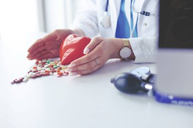 Masada kırmızı kalbi ve steteskopu olan kardiyolog.