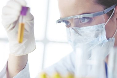 Modern laboratuvar veya hastanede plastik tıbbi tüplerle çalışan araştırmacı, doktor, bilim adamı veya laboratuvar asistanı