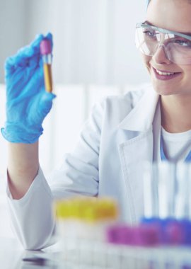 Laboratuvarda sıvı yeşil çözeltiye bakan bir tıbbi veya bilimsel araştırmacı ya da doktor