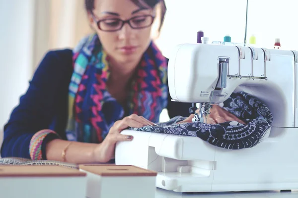 Young woman sewing while sitting at her working place — Stock Photo, Image