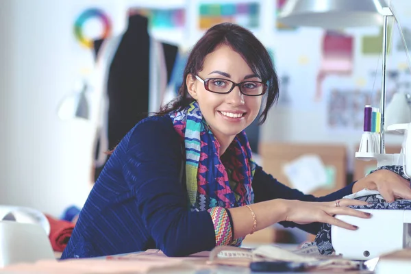 Young woman sewing while sitting at her working place — Stock Photo, Image