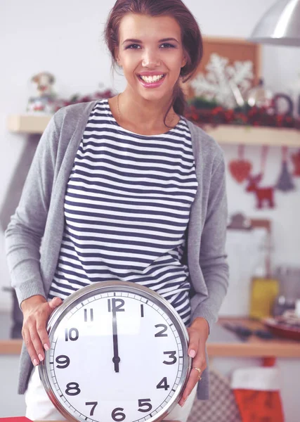 Happy young woman showing clock in christmas decorated kitchen — Stock Photo, Image