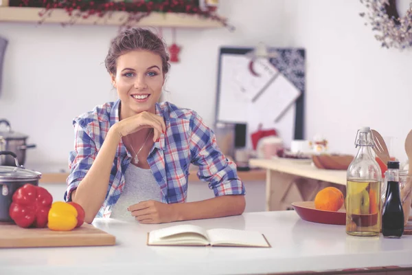 Lächelnde junge Frau in der Küche, isoliert auf weihnachtlichem Hintergrund — Stockfoto