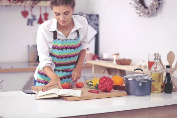 Молодая женщина читает поваренную книгу на кухне, ищет рецепт — стоковое фото
