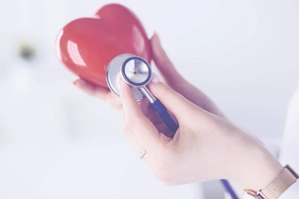A doctor with stethoscope examining red heart, isolated on white background — Stock Photo, Image