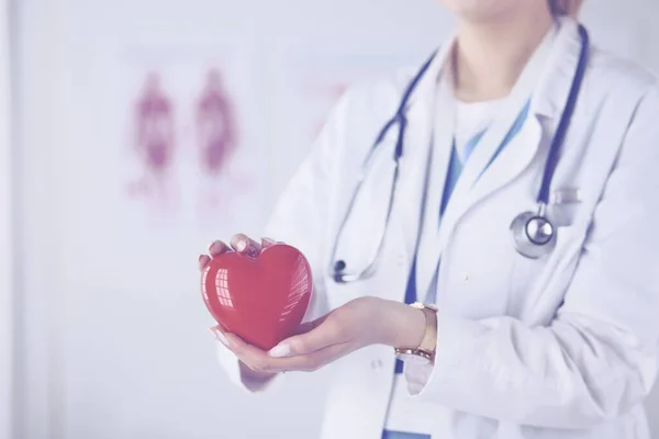 Médica com estetoscópio segurando coração, em fundo claro — Fotografia de Stock