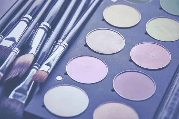 Pinceles de maquillaje y sombras de maquillaje en el escritorio —  Fotos de Stock