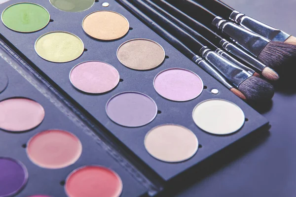 Makeup brushes and make-up eye shadows on desk — Stock Photo, Image