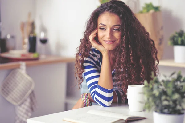 Glimlachende jonge vrouw in de keuken, geïsoleerd op de achtergrond — Stockfoto