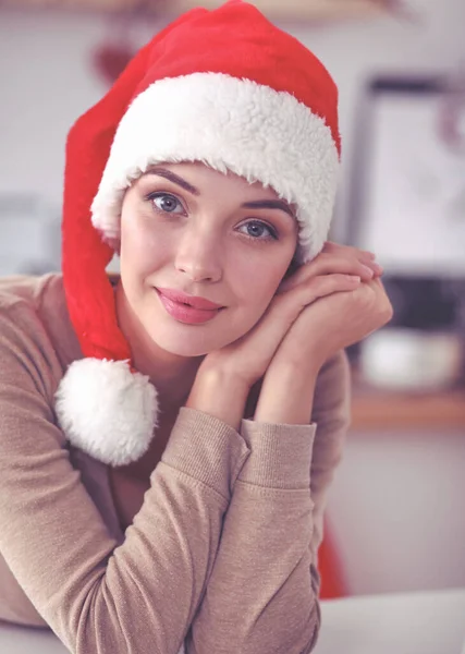 Lächelnde junge Frau in der Küche, isoliert auf weihnachtlichem Hintergrund — Stockfoto