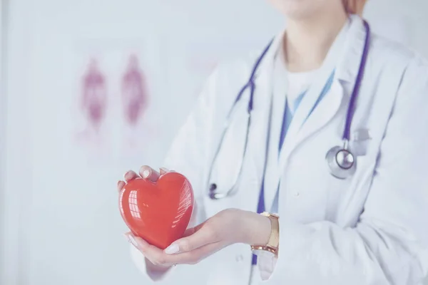 Женщина-врач со стетоскопом, держащая сердце на светлом фоне — стоковое фото
