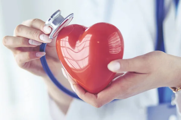 Un medico con stetoscopio che esamina il cuore rosso, isolato su sfondo bianco — Foto Stock