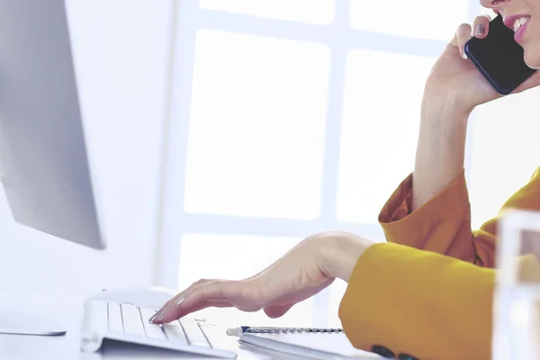 Ritratto di bella donna che chiama mentre siede sul posto di lavoro davanti al computer portatile e lavora a un nuovo progetto — Foto Stock