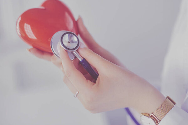 Врач со стетоскопом, изучающий красное сердце, изолированный на белом фоне