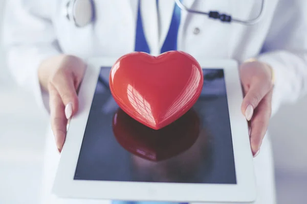 Female doctor with stethoscope holding heart, on light background — Stock Photo, Image