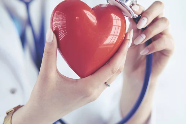 Un medico con stetoscopio che esamina il cuore rosso, isolato su sfondo bianco — Foto Stock