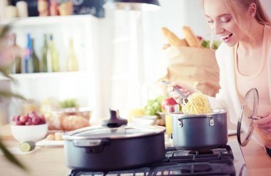 Evdeki mutfakta yemek pişiren güzel genç bir kadın.