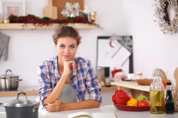 Leende ung kvinna i köket, isolerad på jul bakgrund — Stockfoto