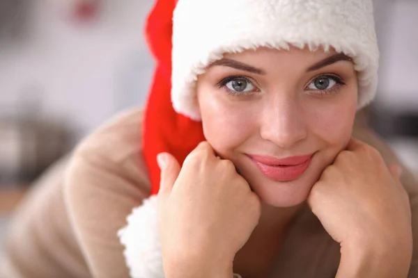 Улыбающаяся молодая женщина на кухне, изолированная на рождественском фоне — стоковое фото