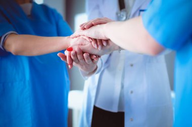 Doktorlar ve hemşireler tıbbi bir ekipte el ele tutuşuyorlar.