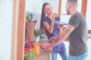 Bir çift evdeki mutfaklarında birlikte yemek pişiriyor.