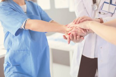 Doktorlar ve hemşireler tıbbi bir ekipte el ele tutuşuyorlar.