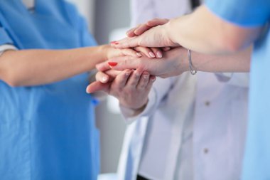 Doktorlar ve hemşireler tıbbi bir ekipte el ele tutuşuyorlar.