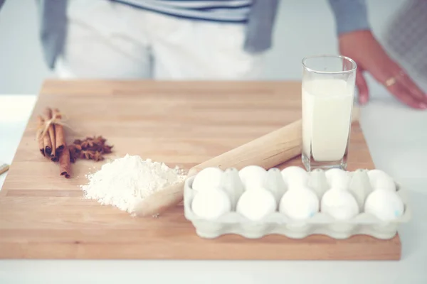 Fondo para hornear con huevos, huevos crudos en un plato, cáscaras de huevo, harina, rodillo y batidor sobre un fondo de madera — Foto de Stock