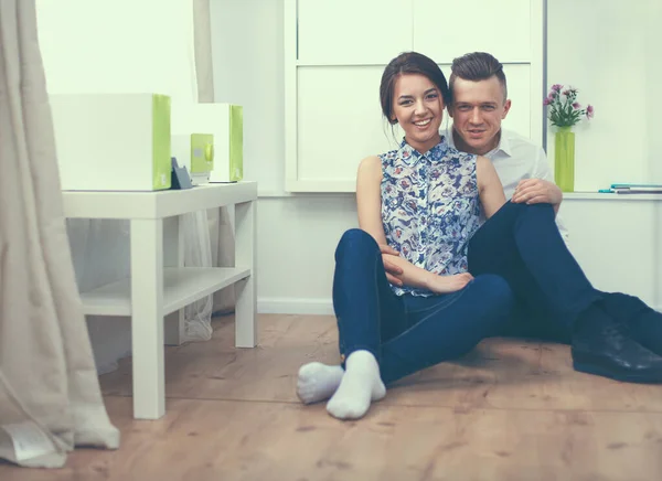 Feliz jovem casal sentado juntos no chão — Fotografia de Stock