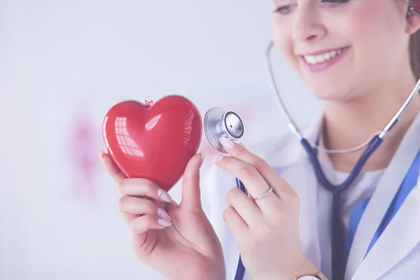 Un médecin avec stéthoscope examinant le cœur rouge, isolé sur blanc — Photo