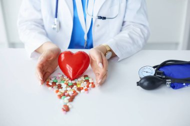 Masada kırmızı kalbi ve steteskopu olan kardiyolog.