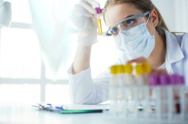 Hastanedeki kan örneğini analiz eden güzel bir kadın laboratuvar asistanı portresi.