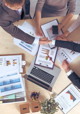 İş adamları el sıkışır, masada otururlar.