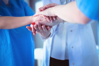 Doktorlar ve hemşireler tıbbi bir ekipte el ele tutuşuyorlar.