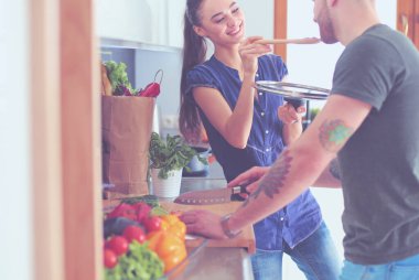 Bir çift evdeki mutfaklarında birlikte yemek pişiriyor.