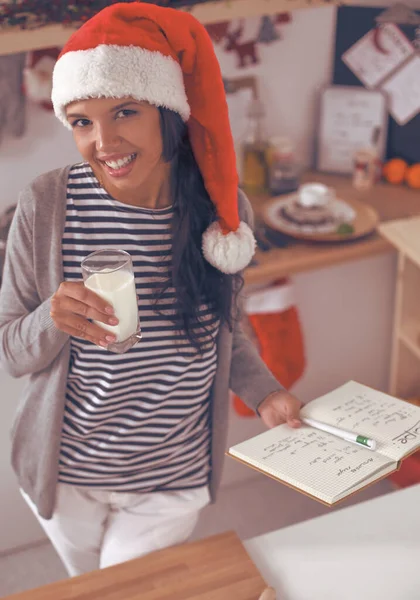 幸せな若い女性笑顔幸せを持って楽しみますクリスマスの準備を身に着けているサンタの帽子 — ストック写真