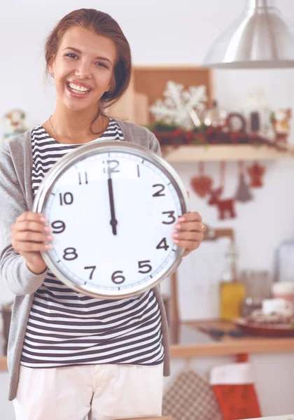 Happy young woman showing clock in christmas decorated kitchen — Stock Photo, Image